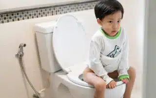 A boy is sitting on toilet with suffering.